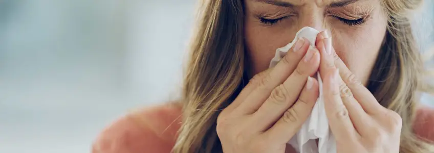 mulher a limpar o nariz com lenço de papel