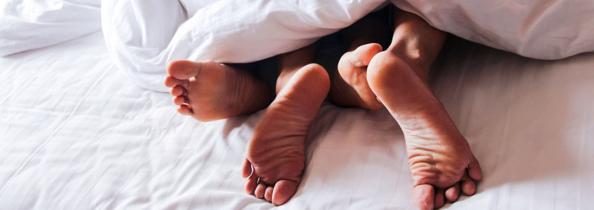 casal na cama com os pés entrelaçados