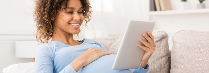 mulher grávida com mão na barriga a olhar para imagem de ecografia