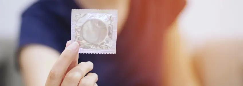 mulher com embalagem de preservativo na mão