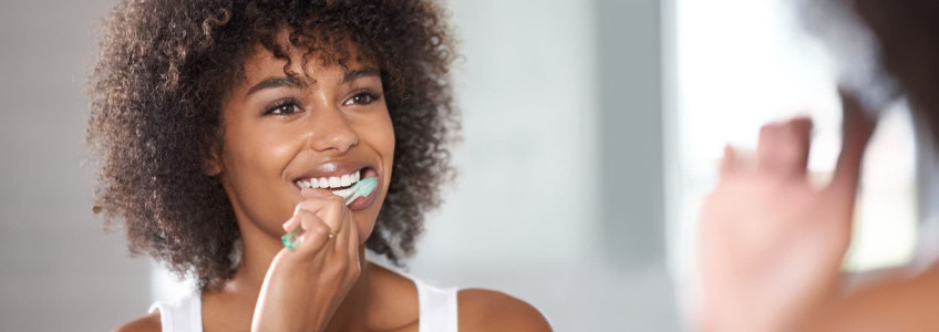 mulher a colocar pasta de dentes na escova elétrica