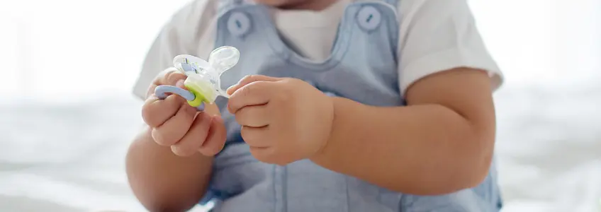 bebé com uma chupeta na mão