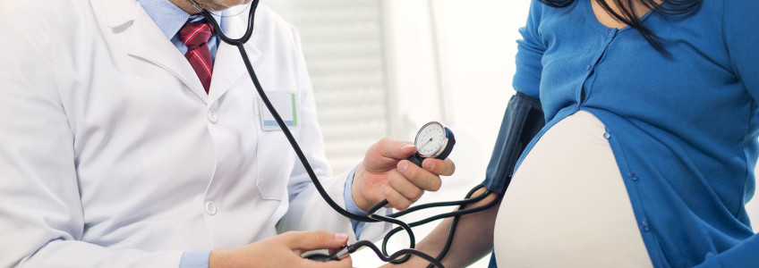 médico a medir a tensão de mulher grávida